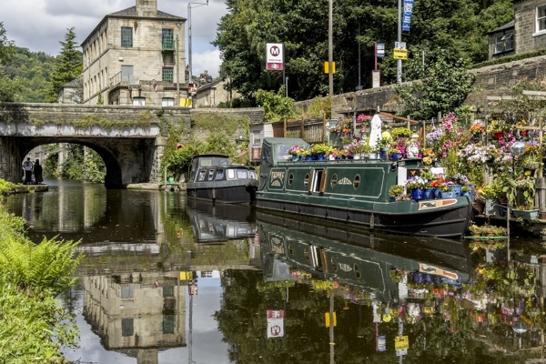 A green narrowboat beside a towpath at Hebden Bridge