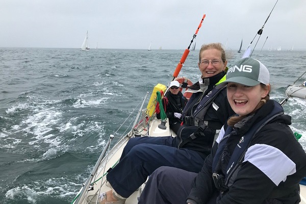 Two women smiling on a boat against a rough sea